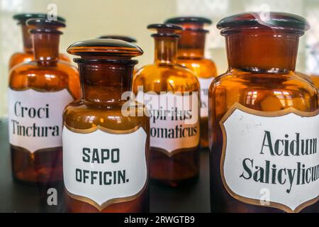 Vasetti antichi in vetro ambrato / bottiglie con spiritus aromaticus, acidum salicylicum, Saponaria officinalis, Croci tinctura in farmacia d'epoca Foto Stock