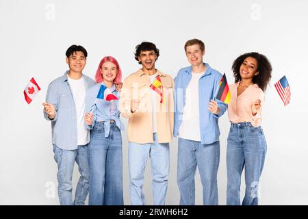 Scambio di studenti, apprendimento delle lingue. Felici amici multirazziali in un ambiente informale, con bandiere di paesi diversi Foto Stock