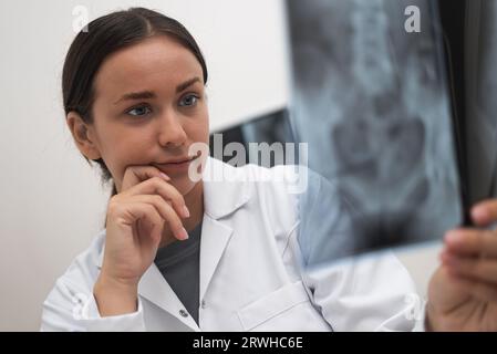 Primo piano del medico preoccupato esamina la pellicola radiologica per valutare le condizioni del paziente Foto Stock