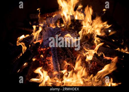 Grande falò di notte. La legna da ardere brucia all'aria aperta. Fiamma gialla. Temperatura di combustione elevata. Foto Stock