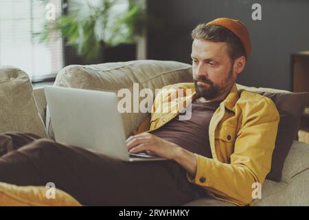 L'uomo stanco si prende una meritata pausa sulla sedia da ufficio, reclinandosi e sdraiandosi dopo una lunga ed estenuante giornata di lavoro. Trovare conforto e sollievo nel mondo aziendale, in cui i momenti di riposo diventano una preziosa necessità di ringiovanimento. Foto di alta qualità Foto Stock