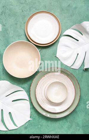 Set di stoviglie pulite ed eleganti e foglie di carta su sfondo verde Foto Stock