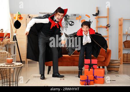 Il bambino spaventoso e suo padre vestiti per Halloween come vampiri a casa Foto Stock