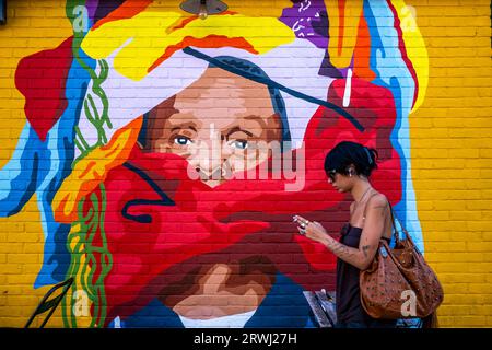 A Young Woman passeggia davanti a Colourful Street Art, Shoreditch, Londra, Regno Unito. Foto Stock