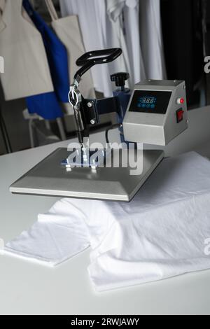 Stampa logo. Pressa a caldo con t-shirt su tavolo bianco Foto Stock