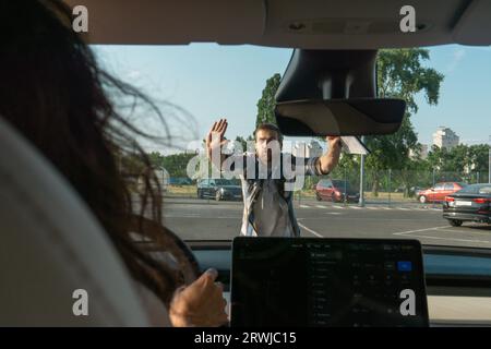 Istruttore maschio che mostra il gesto di stop mentre insegna alle donne a parcheggiare un'auto nella scuola di guida. Test di guida, corsi per conducenti, concetto di esame Foto Stock