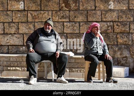 Gli uomini locali si raffreddano sotto il sole fuori dal Convento di San Tellano a Maaloula, una città cristiana di lingua aramaica costruita sulle aspre montagne della Siria Foto Stock