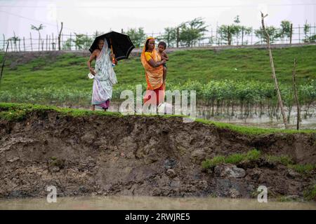 Khulna, Bangladesh. 25 agosto 2023. Donne viste in piedi sulla riva rotta del fiume Shibsha a Dakop Upazilla, Khulna. Non molto tempo fa Kalabogi, un villaggio costiero del Bangladesh, era pieno di terra coltivabile fino a quando l'innalzamento del livello del mare non cominciò a ingoiare l'area fino alla baia del Bengala. Frequenti cicloni e inondazioni hanno colpito il villaggio dalla fine degli anni '1990 Nel 2009, un grande ciclone chiamato Aila distrusse i 1.400 chilometri di argini, 8.800 chilometri di strade e circa 50.000 ettari di terreno agricolo. Diverse centinaia di persone sono state uccise nel disastro. La Foto Stock