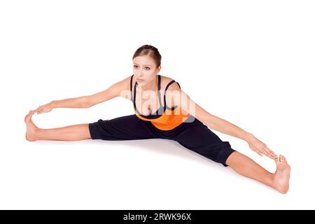 Donna che fa la prima fase dell'esercizio yoga chiamato posa grandangolare seduta, nome sanscrito: Upavista Konasana, questa posa libera la colonna vertebrale e le articolazioni dell'anca Foto Stock