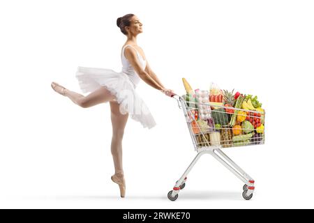 Foto a profilo completo di una ballerina che balla e spinge un carrello con prodotti alimentari isolati su sfondo bianco Foto Stock