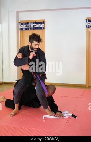 Due uomini che praticano il Jiu-Jitsu brasiliano combattendo alla scuola. Addestramento BJJ. Foto Stock