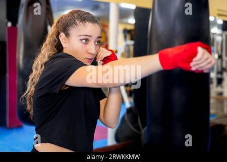 Pugile femminile che si allenano e colpiscono una borsa da pugilato. Combattere lo sport. Foto Stock