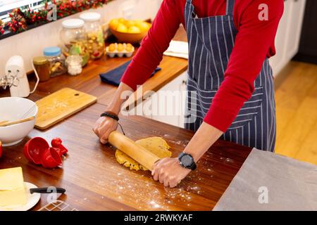 Uomo birazziale che indossa grembiule che prepara biscotti di natale in cucina Foto Stock