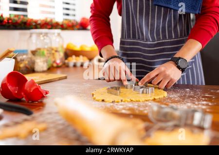 Uomo birazziale che indossa grembiule che prepara biscotti di natale in cucina Foto Stock