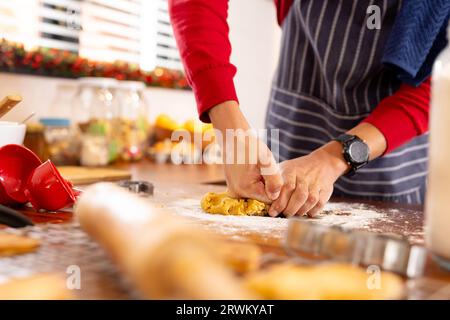 Uomo birazziale che indossa grembiule che prepara biscotti di natale in cucina Foto Stock