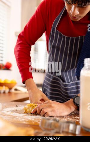 Uomo birazziale che indossa grembiule che prepara biscotti di natale in cucina Foto Stock