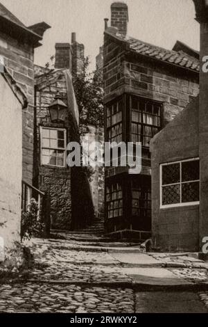 Strada lastricata in pendenza a Robin Hoods Bay, un villaggio sulla costa del North Yorkshire in Inghilterra, quasi 100 anni fa. Fotografia d'epoca scattata nel 1926, da una collezione della famiglia Yorkshire. Foto Stock