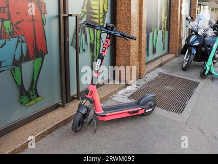 E-scooter parcheggiato sul marciapiede di fronte a un negozio a Milano, Italia Foto Stock