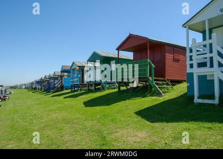 Piccole case sulla spiaggia di Tankerton sulle pendici di Tankerton sul lungomare di Whitstable, Kent, Regno Unito. Capanne in legno rialzate con vista mare nelle giornate di sole blu Foto Stock