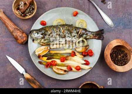 Trota di fiume intera al forno con asparagi bianchi e pomodori. Vista dall'alto. Foto Stock