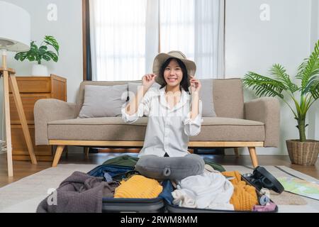 Giovane donna asiatica viaggiatrice imballare le cose in valigia prepararsi per le vacanze a casa. concetto di viaggio per backpacker Foto Stock