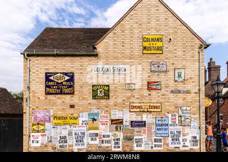 Insegne e poster pubblicitari d'epoca esposti sul lato di un edificio a Blists Hill Victorian Town, Telford, Inghilterra Foto Stock