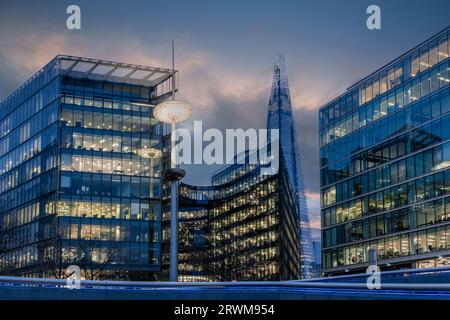 Moderni edifici alti ricoperti di vetro/blocchi di uffici nel centro della città al crepuscolo con luci accese e nuvole di colore nebbioso Foto Stock
