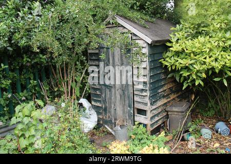 Un recinto di legno Run Down nell'angolo di un giardino. Foto Stock