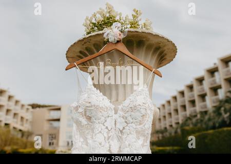 Uno scatto ravvicinato di un abito da sposa bianco appeso su un rack in un parco soleggiato. Foto Stock