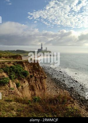 Un panorama mozzafiato sulla spiaggia con uno sfondo sereno e un pittoresco faro sullo sfondo Foto Stock