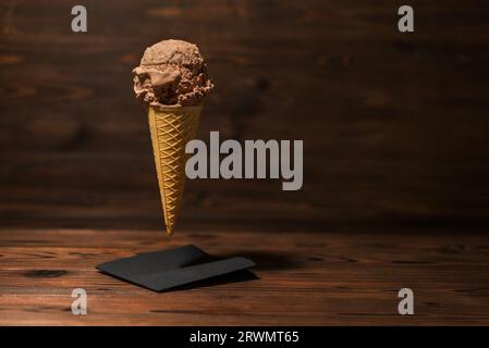 divertente concetto creativo di cono cialde volante con gelato al cioccolato su sfondo di legno, concetto, spazio copia. Foto Stock