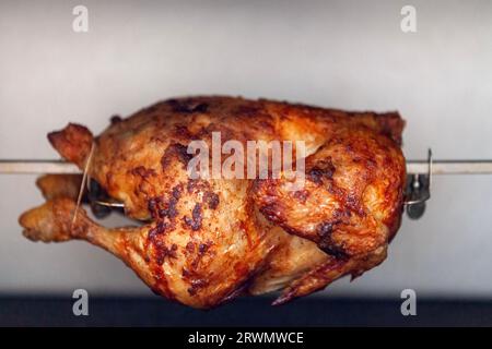 Un pollo arrosto è un piatto di pollo che viene cotto su un girarrosto utilizzando il calore diretto in cui il pollo viene posto accanto alla fonte di calore. Foto Stock