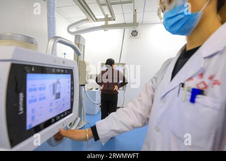 LUANNAN COUNTY, Cina - 11 febbraio 2022: Il medico ha indicato al paziente di posare davanti alla macchina per fluoroscopia a raggi X e di prepararsi per i raggi X. Foto Stock