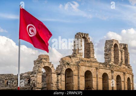 La bandiera tunisina di fronte alle rovine dell'anfiteatro romano di El Jem in Tunisia. Foto Stock