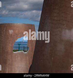 Guardando attraverso la scultura del castello di sabbia di Richard Broderick sul lungomare centrale di Whitley Bay verso il faro di St Mary Foto Stock