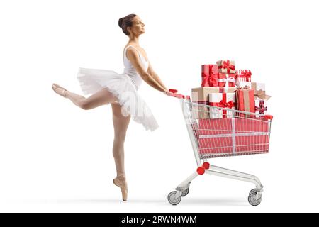 Foto a profilo completo di una ballerina che balla e spinge un carrello con regali isolati su sfondo bianco Foto Stock