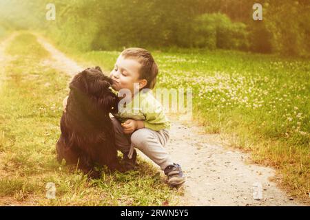 Bambino Cyte con un cane che cammina nel parco estivo. Bambino che gioca con il cane in natura. Foto Stock