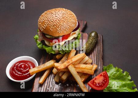 Hamburger fatti in casa con ingredienti di manzo, pomodori, lattuga, formaggio, cipolla, i cetrioli e le patatine fritte sul tagliere e rusty sfondo. Vista dall'alto. Foto Stock