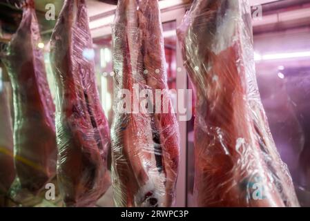 Le carcasse di maiale macellato sono appese in una macelleria. Foto Stock