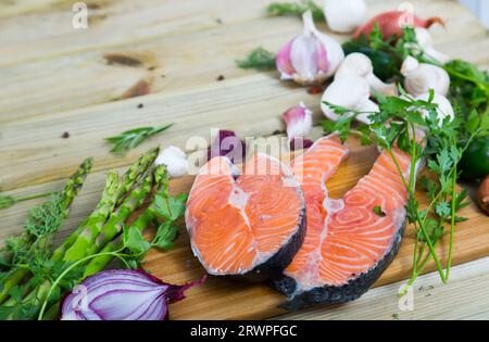 Cibo cornice di bistecche di salmone, verdure, funghi su superficie di legno Foto Stock