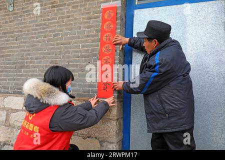 LUANNAN COUNTY, Cina - 24 gennaio 2022: I contadini postano distici rossi alla porta alla vigilia del Festival di primavera Foto Stock