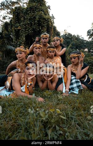 I balinesi si divertono insieme ai loro amici in costumi dorati dopo lo spettacolo di danza all'interno del villaggio Foto Stock