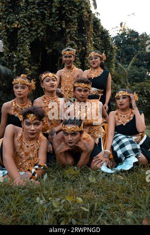 I balinesi si divertono insieme ai loro amici in costumi dorati dopo lo spettacolo di danza all'interno del villaggio Foto Stock