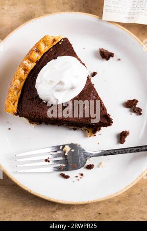 Fetta di torta brownie ricoperta di panna montata Foto Stock