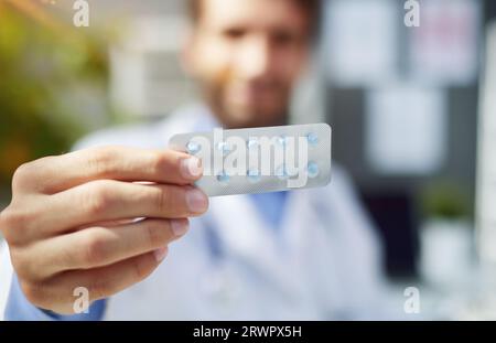 Ritratto ravvicinato dell'attraente farmacia del doc che tiene in mano una bottiglia di pillole organiche Foto Stock