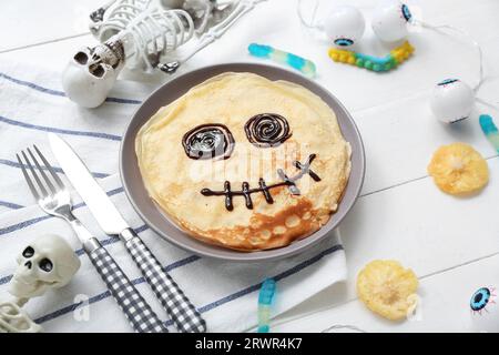 Composizione con divertenti pancake di Halloween e decorazioni su sfondo di legno chiaro Foto Stock