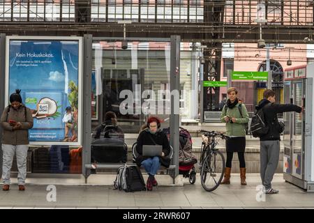 Foto di una donna che lavora sul suo portatile, a distanza, dalla piattaforma della stazione ferroviaria di Koln Hbf a Colonia, Germania. Köln Hauptbahnhof o Colog Foto Stock