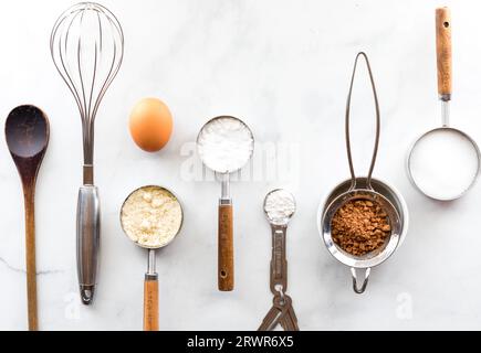 Una fila di vari utensili da forno con ingredienti su un tavolo in marmo bianco. Foto Stock