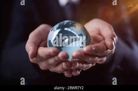 un uomo d'affari tiene il globo di vetro con i continenti in mano Foto Stock
