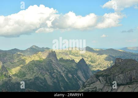 Le folte nuvole di cumulus gettano un'ombra su una pittoresca valle tra le montagne con picchi in un giorno d'estate. Parco naturale Ergaki, regione di Krasnoyarsk Foto Stock